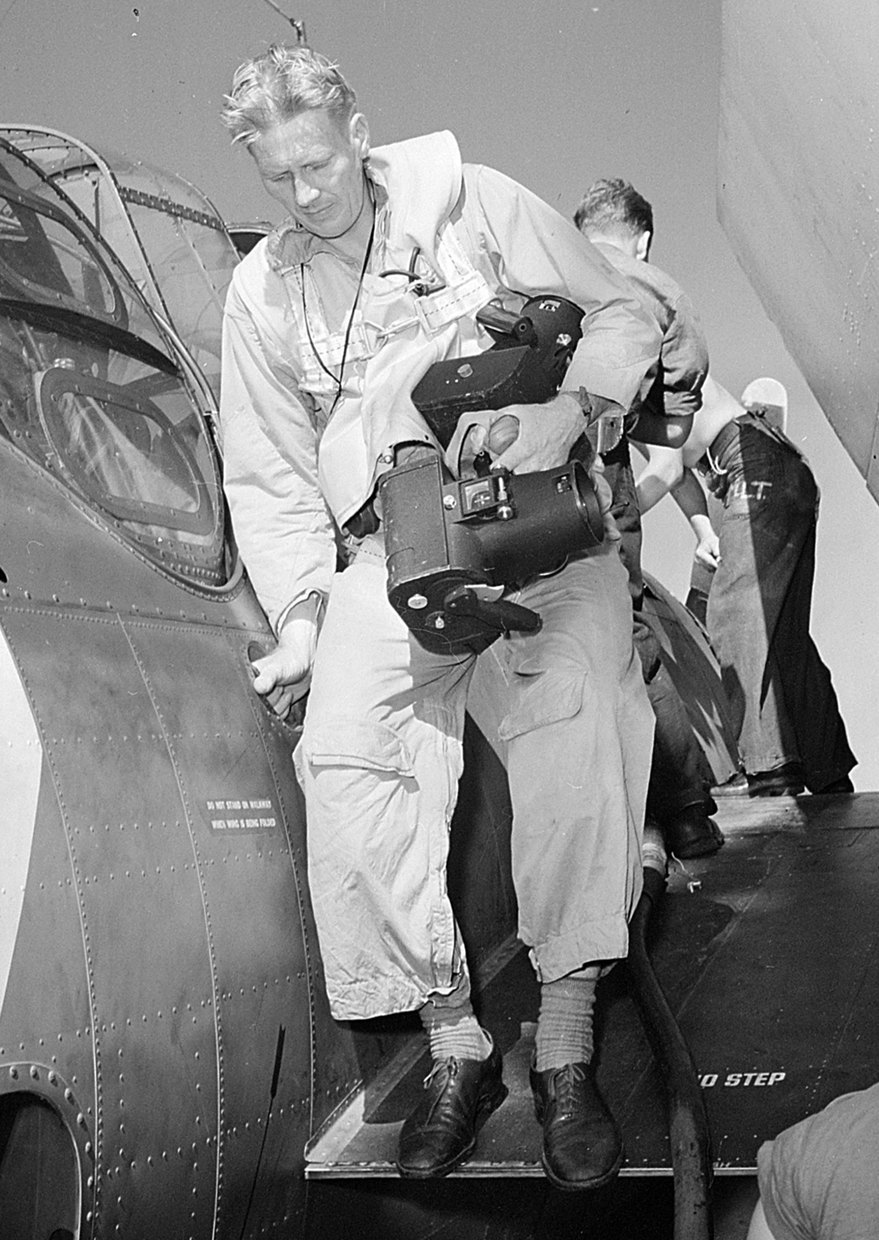 Lieutenant Charles Kerlee steps down from a TBF Avenger wing carrying two Fairchild K-20 cameras